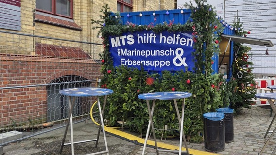 Der Glühweinstand der Marinetechnikschule von der Seite aufgenommen. Weihnachtlich dekoriert, davor stehen zwei Stehtische. Ein Banner wirbt für Punsch und Suppe. © Förderverein STRALSUND MUSEUM e.V. Foto: Gabriele Warmbier