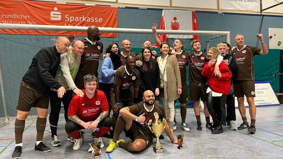 Jubelnde Fußball-Herrenmannschaft versammelt vor einem Tor in der Halle. © NDR - Stefan Thoms Foto: Stefan Thoms