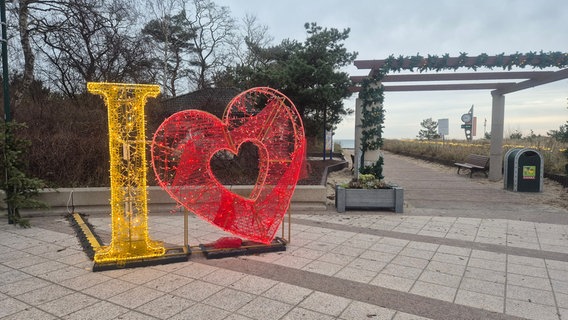 Ein "I Love" Dekoaufsteller am Aufgang zum Strand auf der Karlshagener Promenade. Das rote Netz des Herzens ist von Randalierern abgerissen worden und hängt herunter. © NDR Foto: Dörte Rochow