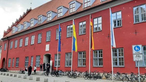 Der Haupteingang der Greifswalder Rathauses, davor stehen Fahrräder, einige Fahnen wehen vor dem Gebäude © M. Klemme Foto: M. Klemme