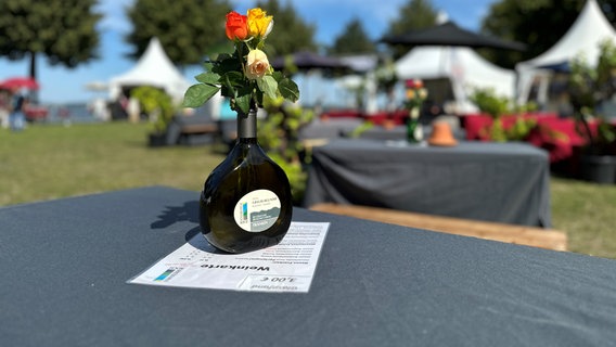 Eine Flasche mit Blumen steht auf einem Stehtisch beim Weinfest in Stralsund. © Rebekka Bahr Foto: Rebekka Bahr