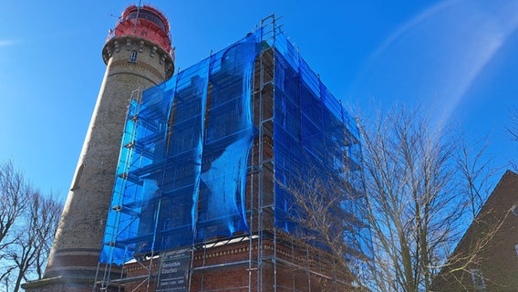 Der Schinkelturm am Kap Arkona ist mit einem Baugerüst und einem blauen Netz verkleidet. © Andreas Heinemann 