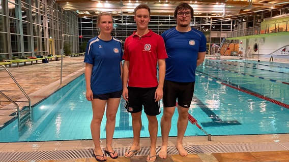 Auf dem Bild sind drei ausgebildete Rettungstrainer zu sehen, die im Freizeitbad Greifswald vor dem Schwimmerbecken stehen. © NDR Foto: Paula Deusing