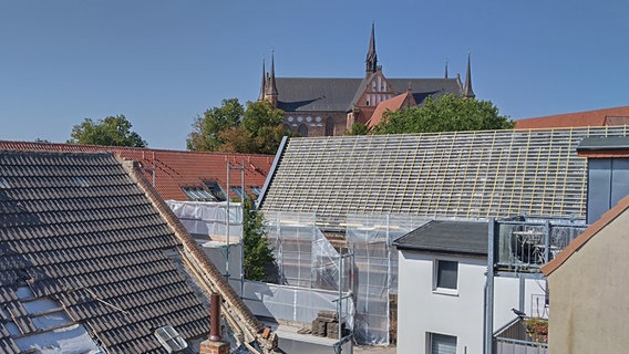 Blick auf die Sankt-Georgen-Kirche in Wismar. Davor ist die Baustelle des Eingangs des Antoniter-Hofes zu sehen. Das Gebäude ist eingerüstet und das Dach wird gerade gedeckt. © NDR Foto: Christoph Woest