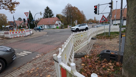 Eine Baustelle entlang der Fahrbahnen einer Kreuzung mit Schildern, Fahrzeugen und weiß-roten Straßenbaken © Christoph Loose Foto: Chris Loose