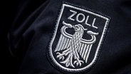 Das Zoll-Abzeichen auf der Uniform eines Beamten - der Bundesadler in silbergrau auf schwarzem Grund mit dem Schriftzug "Zoll" in Großbuchstaben darüber. © NDR Foto: Sina Schuldt