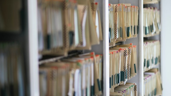 In Reihe sortierte Aktenmappen in einem Schrank. © NDR Foto: Julius Matuschik