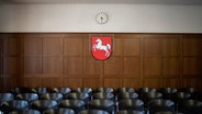 In einem Gerichtssaal hängt hinter mehreren Stuhlreihen das Wappen des Landes Niedersachsen. © NDR Foto: Julius Matuschik