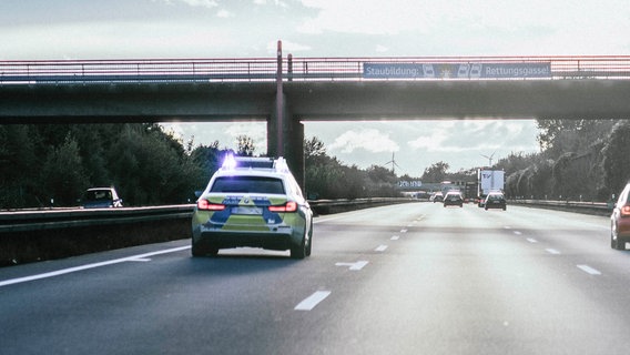 Ein Einsatzfahrzeug der Autobahnpolizei fährt mit eingeschaltetem Blaulicht auf einer dreispurigen Autobahn. © NDR Foto: Julius Matuschik