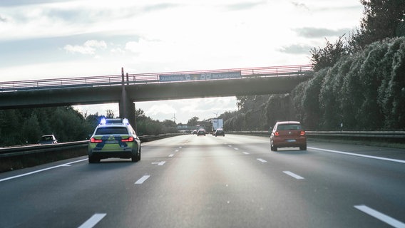 Ein Einsatzfahrzeug der Autobahnpolizei fährt mit eingeschaltetem Blaulicht auf einer dreispurigen Autobahn. © NDR Foto: Julius Matuschik