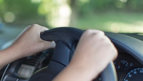 Ein Teenager am Lenkrad eines Autos. (Themenbild: unerlaubtes Autofahren) © dpa / Westend61 | zerocreatives 