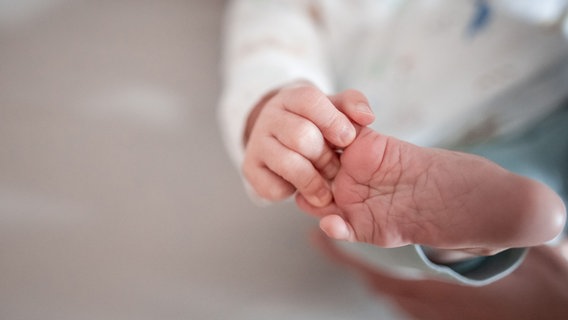 Ein Baby greift mit den Fingern nach seinem Fuß. © dpa-Bildfunk Foto: Fabian Strauch/dpa