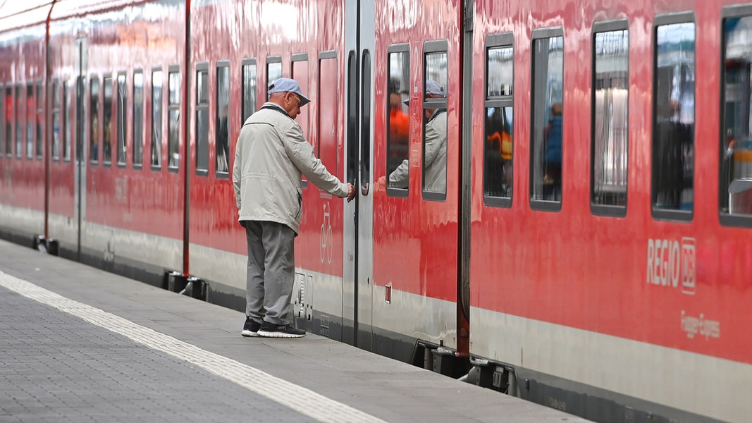 Ein Rentner steigt in einen Zug ein. 