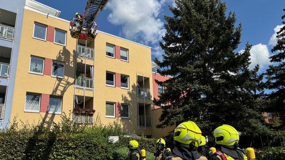 Feuerwehrleute mit Atemschutz und eine Drehleiter vor einem Mehrfamilienhaus. © Feuerwehr Göttingen 