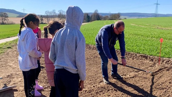 Schule mal anders: Kinder schauen in der Baurnhof AG dabei zu, wie ein Mann ein Feld beackert. © Landvolk Northeim-Osterode Kreisbauernverband e.V. 