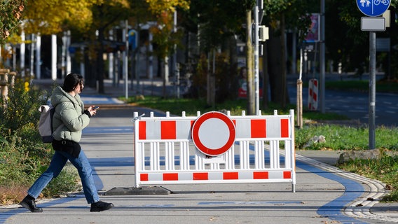 Eine Passantin geht an einer Straßensperrung vorbei. © Swen Pförtner/dpa Foto: Swen Pförtner