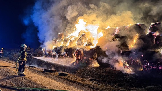 Einsatzkräfte der Feuerwehr versuchen hunderte brennende Strohballen zu löschen. © Kreisfeuerwehr Northeim Foto: Joel Fröchtenicht