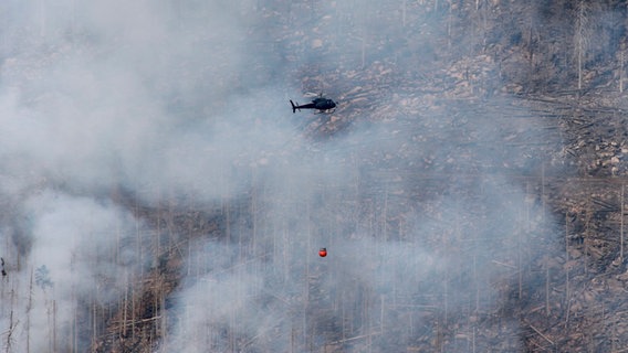 Ein Lösch-Hubschrauber fliegt in der Nähe des Brockens und kämpft gegen den Waldbrand. © dpa Foto: Matthias Bein