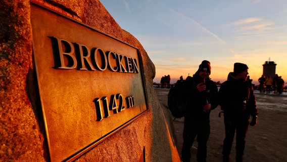 Das Licht der aufgehenden Sonne wird auf einer Brockentafel reflektiert. © dpa-Bildfunk Foto: Matthias Bein