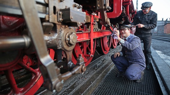 Caleb Lovegrove von der Ffestiniog and Welsh Highland Railways (FR/WHR) aus Wales reinigt mit einem Tuch eine Dampflok an der Einsatzstelle der Harzer Schmalspurbahnen GmbH. © dpa-Bildfunk Foto: Matthias Bein