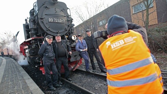 Heizer und Zugführer stehen mit den beiden Gästen (r) von der Ffestiniog and Welsh Highland Railways (FR/WHR) aus Wales für ein gemeinsames Foto vor einer Dampflok. © dpa-Bildfunk Foto: Matthias Bein