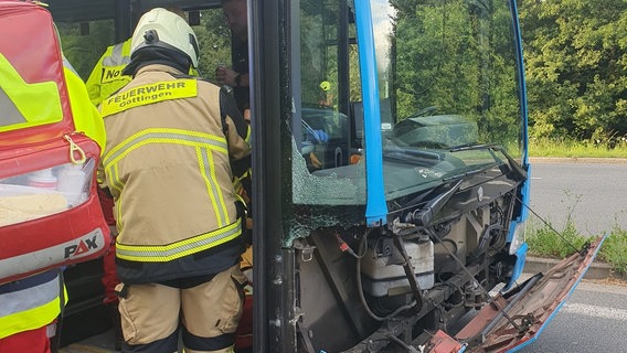 Die Front eines Linienbusses ist beschädigt, ein Feuerwehrmann geht in den Bus hinein. © Feuerwehr Göttingen 