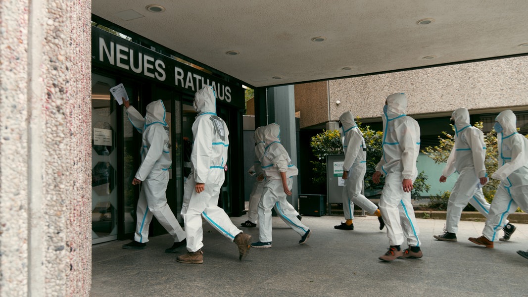 Demonstranten in Maleranzügen gehen auf den Eingang des Göttinger Rathauses zu. 