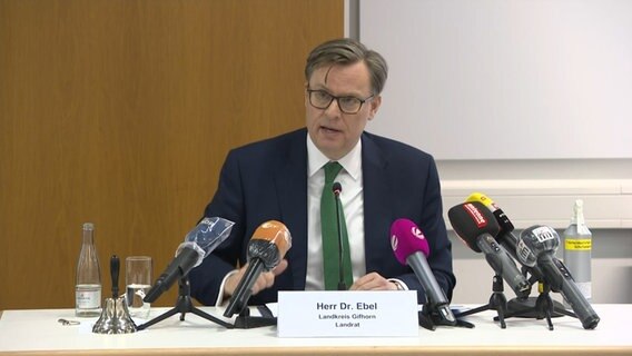 District Administrator Ebel (CDU) sits behind a desk with microphones.  © NDR 