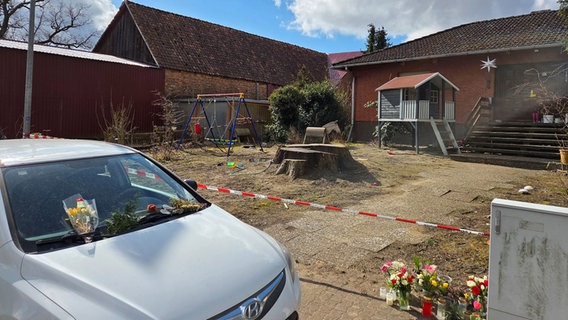 Blumen und Kerzen stehen vor einem Wohnhaus in Rietze. © picture alliance/dpa Foto: Christian Brahmann