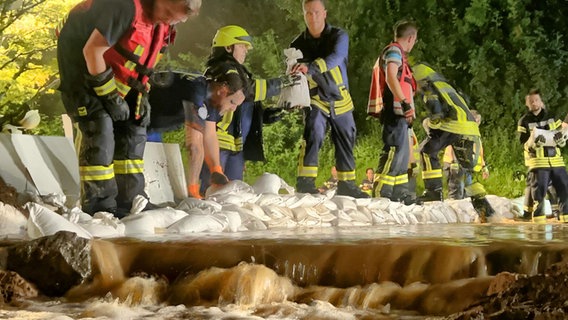 Einsatzkräfte der Feuerwehr stapeln Sandsäcke. © Freiwillige Feuerwehr Stadt Hann. Münden 