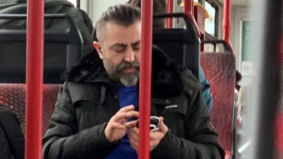 Ein Mann sitzt in der Straßenbahn und guckt auf sein Handy. © Polizei Braunschweig 