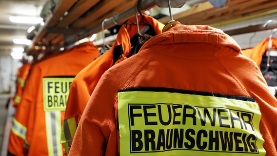 Jacken der Feuerwehr Braunschweig hängen in einem Raum © NDR Foto: Uwe Day