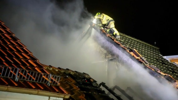 In Göttingen steht ein Feuerwehrmann auf dem Dach eines brennenden Hauses. © TeleNewsNetwork 