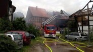 Ein Mehrfamilienhaus im Ortsteils Greene wird gelöscht. Ein Feuerwehrwagen mit Kran steht vor dem Haus. © NDR Foto: Birte Olig