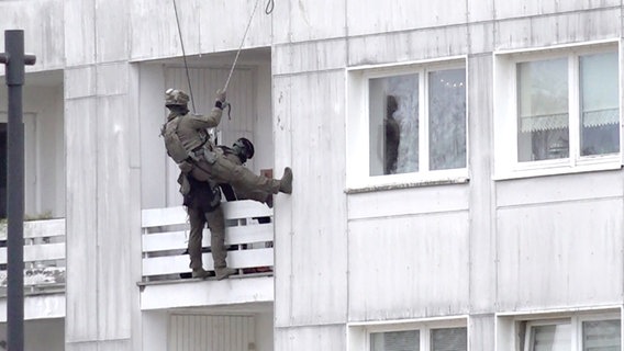 Spezialkräfte der Polizei seilen sich von einem Hochhaus auf einen Balkon in Wolfsburg ab. © aktuell24 