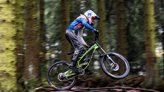 Ein Mountainbiker fährt bei regnerischem Herbstwetter durch den Wald. © dpa-Bildfunk Foto: Swen Pförtner