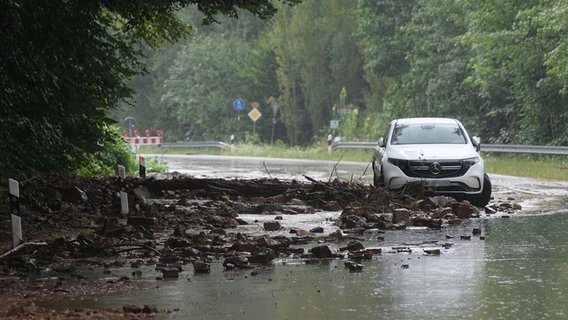 Ein Auto steht neben Geröll auf der Bundesstraße 80 bei Hann. Münden. An der B80 war es zu einem Erdrutsch gekommen. © Swen Pförtner/dpa Foto: Swen Pförtner/dpa