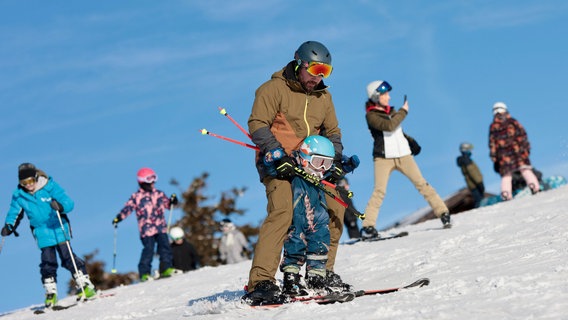 Ein Mann übt mit einem Kind Skifahren am Wurmberg im Harz. © dpa-Bildfunk Foto: Matthias Bein