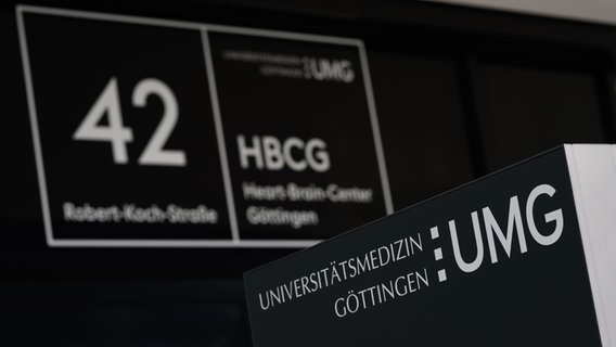 Blick auf den Eingangsbereich eines Gebäudes der Universitätsmedizin Göttingen mit dem Schriftzug "UMG" im Vordergrund und "Heart and Brain Center Göttingen" (HBCG) im Hintergrund. © picture alliance/dpa Foto: Swen Pförtner