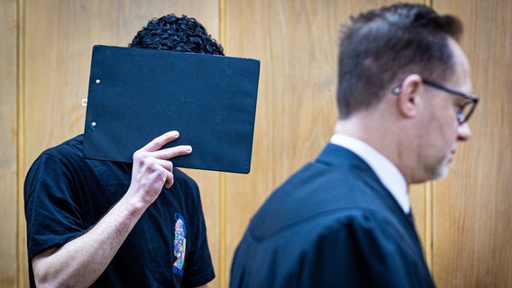 Der Angeklagte verdeckt sein Gesicht mit einer Mappe bei Prozessauftakt in einem Saal im Landgericht Hannover. © dpa-Bildfunk Foto: Moritz Frankenberg