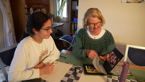 Angasa Safi und Susanne Konerding sehen sich ein Fotoalbum an. © NDR 