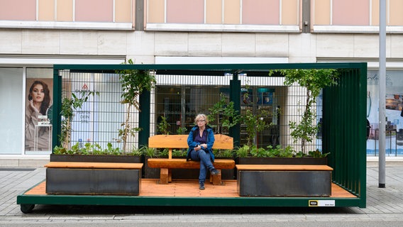 Eine Frau sitzt in einem Klimacontainer in der Göttinger Innenstadt. © dpa Foto: Swen Pförtner