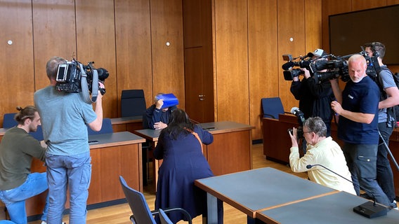 Ein Angeklagter sitzt vor dem Amtsgericht in Brausnchweig und verdeckt sich das Gesicht vor Kameras. © NDR Foto: Sofia Leikam