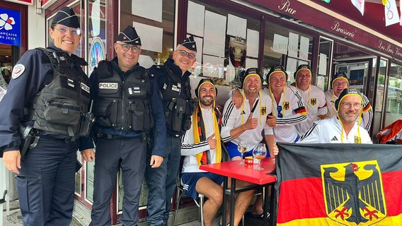 Französische Polizisten lassen sich mit den kostümierten Männer des SV Herta Equord aus Peine bei den Olympischen Spielen in Paris fotografieren. © André Lau 