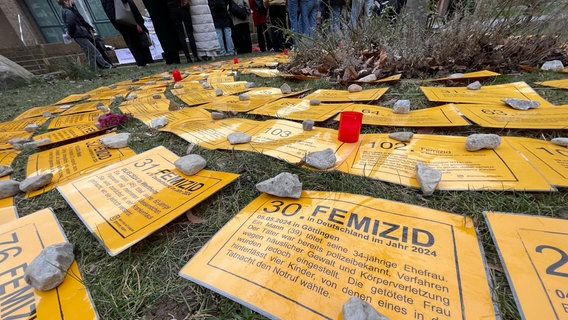 Auf dem Boden liegende gelbe Schilder informieren über die Opfer von Femiziden bei einer Kundgebung vor dem Landgericht in Göttingen. © NDR Foto: Jan Fragel