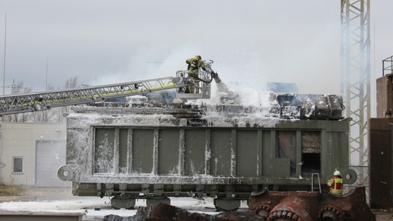 Feuerwehrmann in gelber Schutzausrüstung löscht mit Schaum aus einem Rohr einen Elektrotrafo © Freiwillige Feuerwehr Hohenhameln 