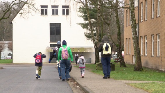 Migranten gehen eine Straße entlang der Landesaufnahme in Braunschweig. © NDR Foto: Alexandra Prelle