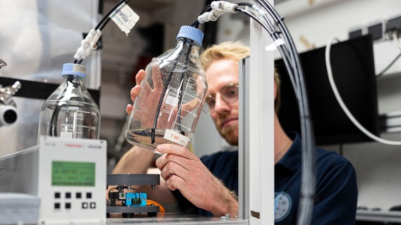 Ein Mann hält eine Flasche mit extrahiertem Wasser in der Hand. © picture alliance/dpa Foto: Michael Matthey