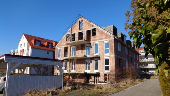 Ein unfertiger Neubau steht inmitten weiterer Mehrfamilienhäuser. © NDR Foto: Marco Schulze