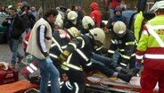 Der Rettungsdienst hebt einen Mann auf eine Trage. viele Menschen stehen durcheinander. Einige machen Fotos und filmen mit ihrern Handys. © NDR.de Foto: Jürgen Jenauer